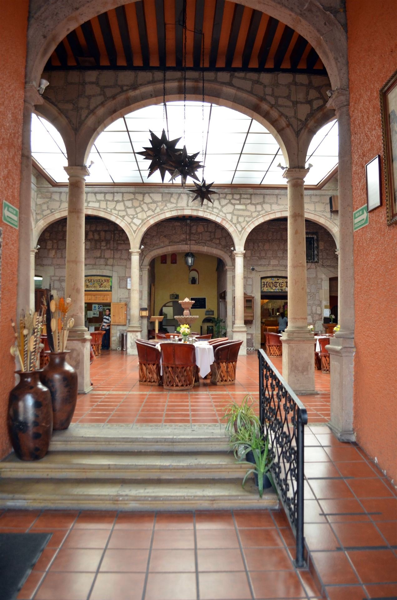 Patio colonial del hotel con arcos de cantera y estrellas de hojalata